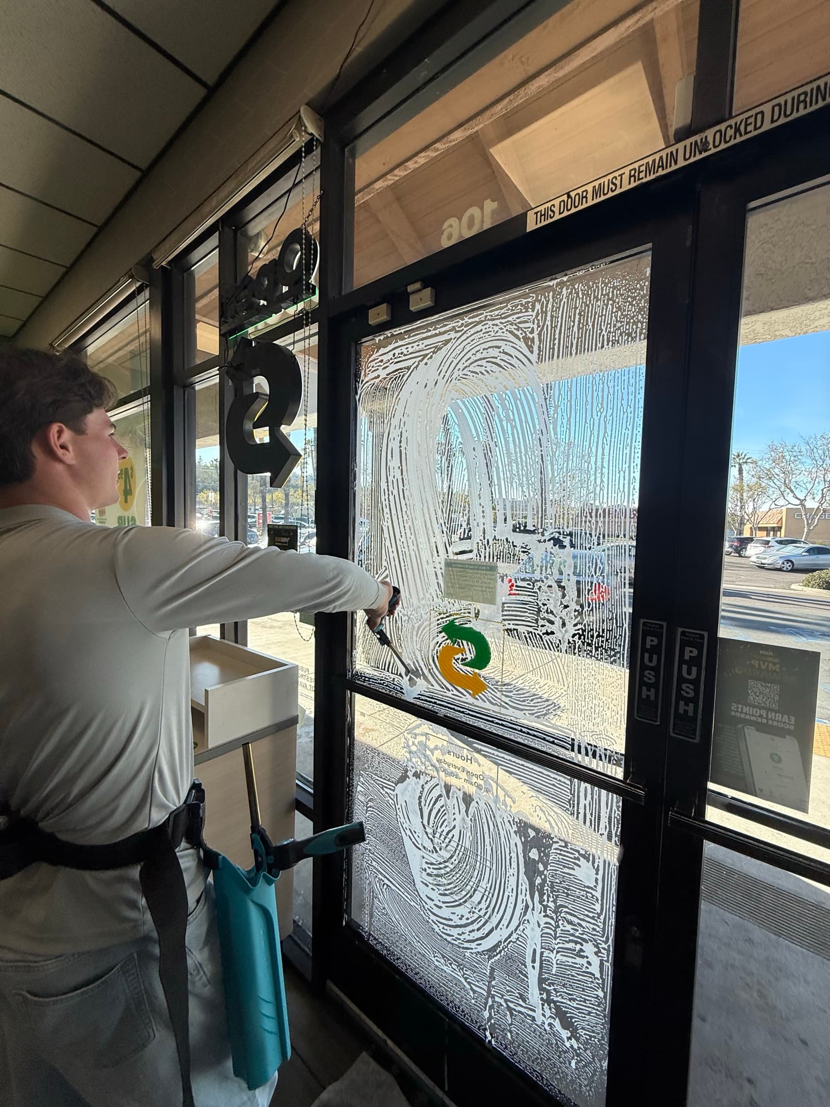 Storefront window cleaning on commercial door glass in El Cajon